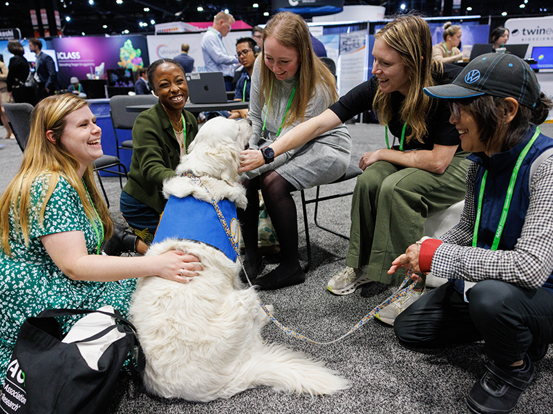 Attendees greet a therapy dog in the Exhibit Hall at the AACR Annual Meeting 2025 in Chicago.